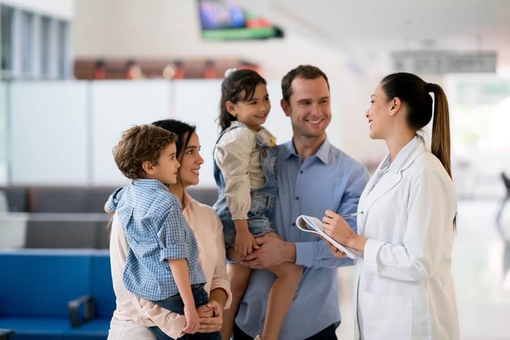 Família sendo atendida por uma médica na recepção de uma clínica